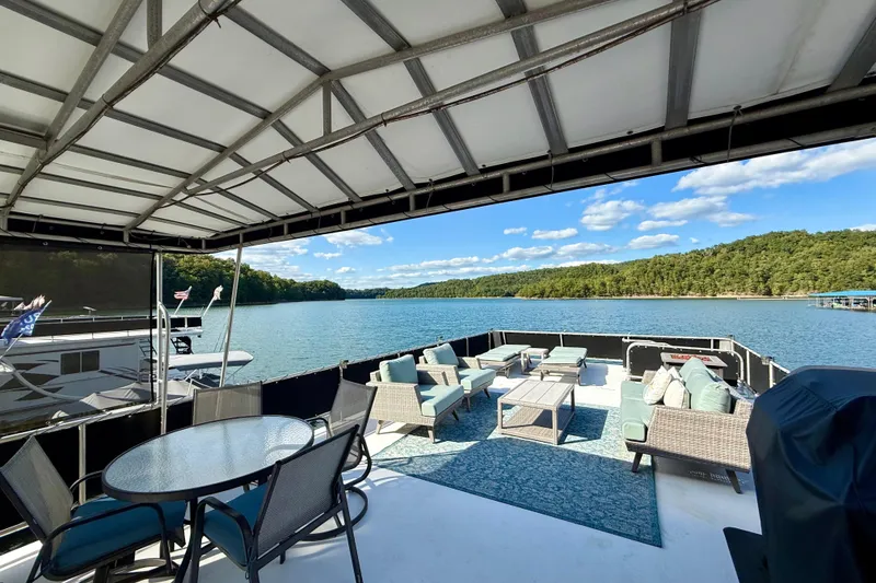 Slide: The Image of Houseboat deck with outdoor seating, overlooking a serene lake and lush green shoreline. - 31