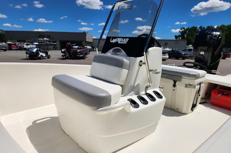 Slide: The Image of 2026 Mako Pro Skiff 17 CC boat interior with seating and console, parked outdoors. - 8