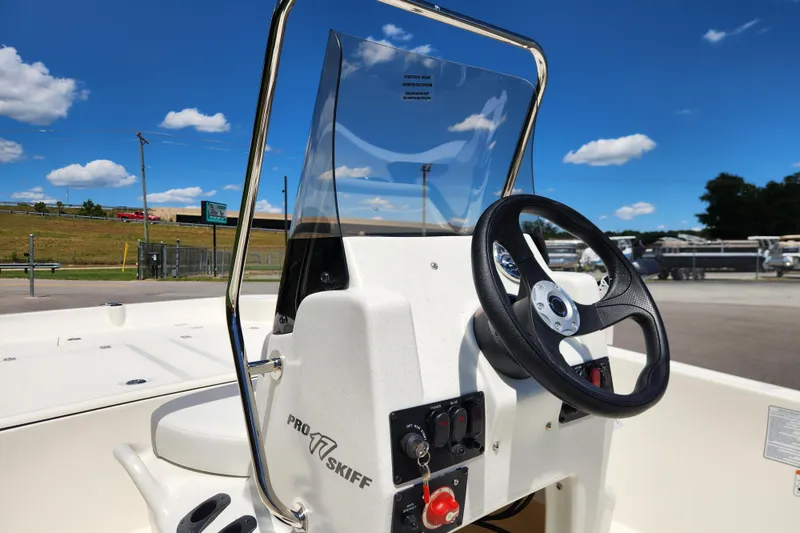 Slide: The Image of 2026 Mako Pro Skiff 17 CC boat console with steering wheel under clear blue sky. - 9