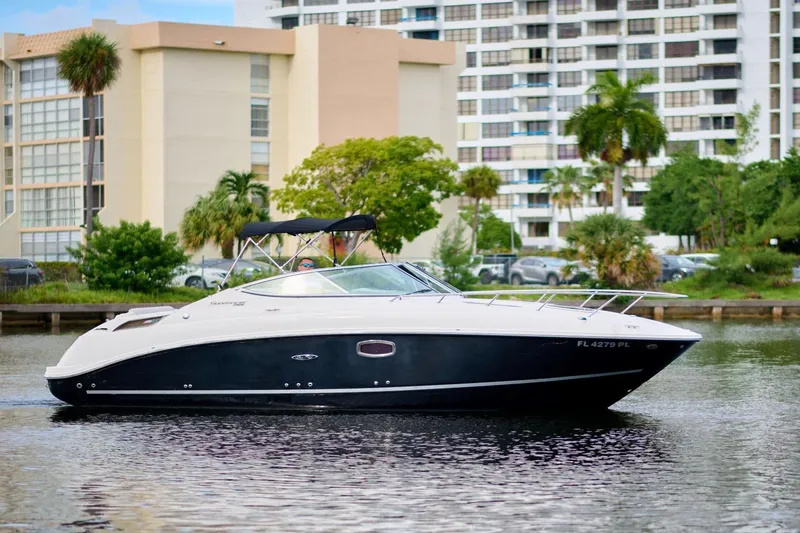 The Image of 2011 Sea Ray 260 Sundancer boat cruising near waterfront buildings and lush greenery. - 0