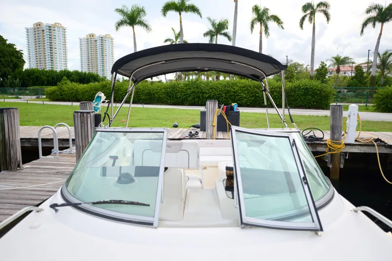Slide: The Image of 2011 Sea Ray 260 Sundancer docked, with open windshield and lush greenery in the background. - 11