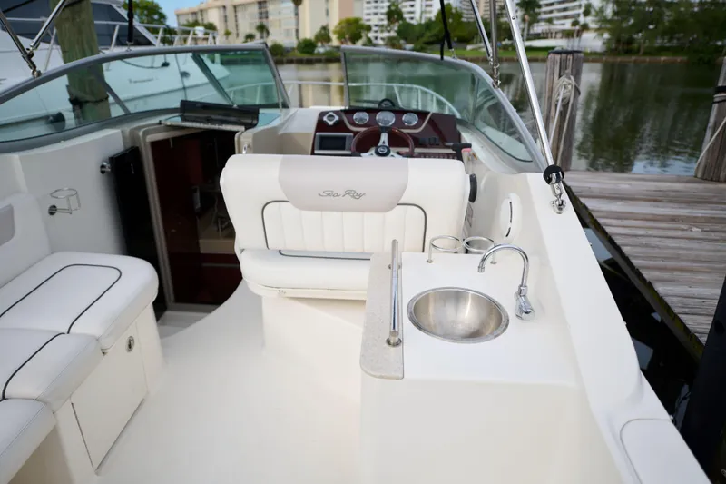 Slide: The Image of 2011 Sea Ray 260 Sundancer interior with seating, sink, and helm near dock. - 8