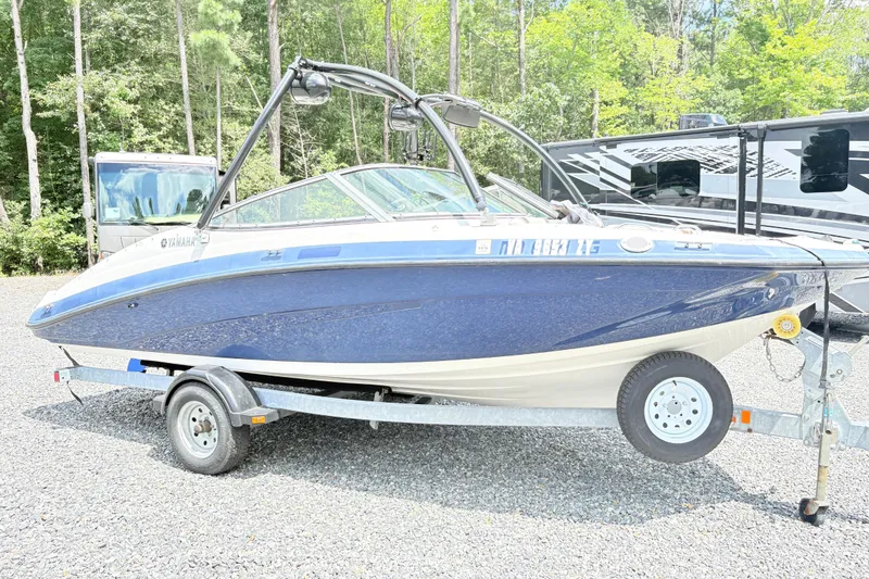 The Image of 2014 Yamaha SX190 boat on trailer, parked outdoors with trees in the background. - 1