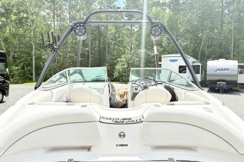 Slide: The Image of 2014 Yamaha SX190 boat with white interior, parked outdoors near RVs and trees. - 10