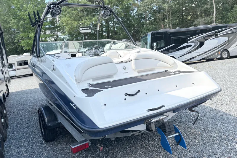 Slide: The Image of 2014 Yamaha SX190 boat on trailer, parked in a gravel lot with RVs. - 14