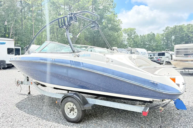 Slide: The Image of 2014 Yamaha SX190 boat on trailer, parked outdoors, surrounded by trees and vehicles. - 4