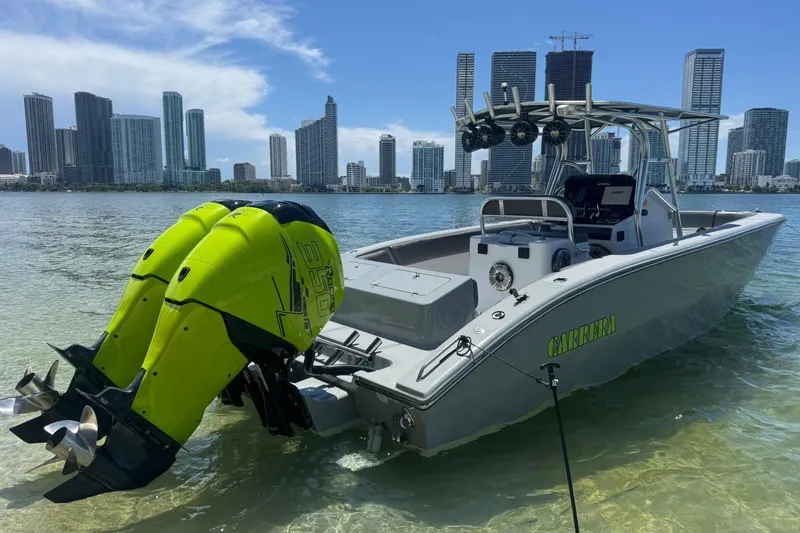 Slide: The Image of 2005 Carrera Boats 32 with neon green lighting and twin outboard motors on a calm lake. - 15