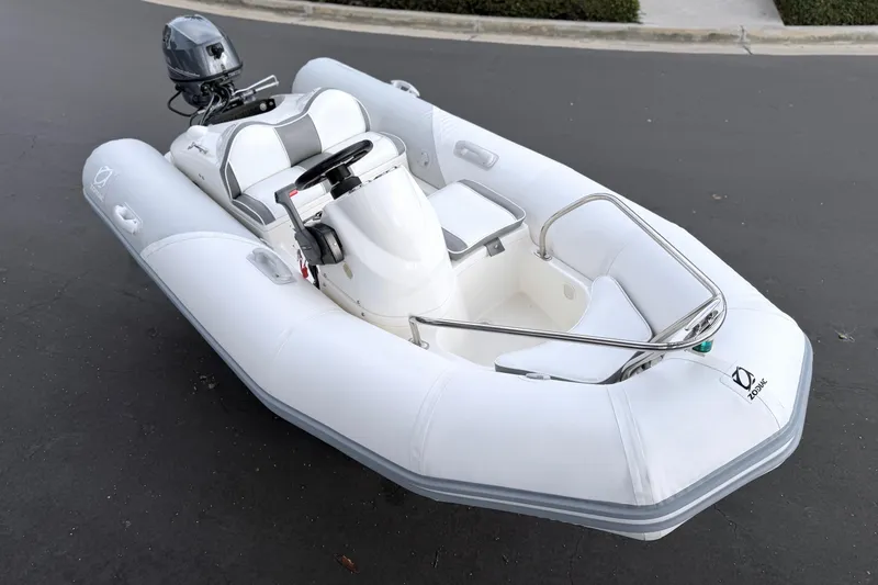 Slide: The Image of 2003 Zodiac Yachtline 340DL inflatable boat with outboard motor, parked on pavement. - 13