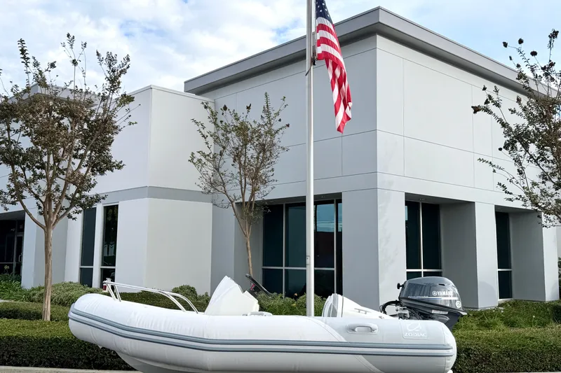 Slide: The Image of 2003 Zodiac Yachtline 340DL inflatable boat near modern building with American flag. - 6