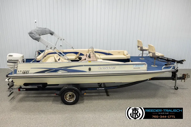 Slide: The Image of 1998 Lowe LS 2220 pontoon boat with Johnson outboard motor, displayed indoors. - 1