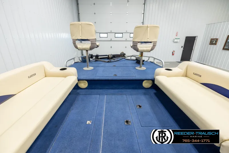 Slide: The Image of 1998 Lowe LS 2220 boat interior with blue carpet and beige seating in a showroom. - 15