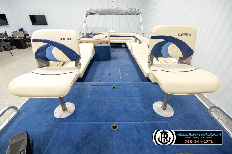 Slide: The Image of 1998 Lowe LS 2220 boat interior with blue carpet and beige seating in showroom. - 17