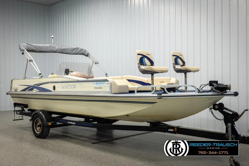 Slide: The Image of 1998 Lowe LS 2220 boat on trailer in indoor showroom, featuring dual seats and canopy. - 2