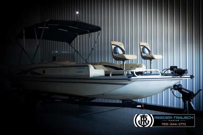 Slide: The Image of 1998 Lowe LS 2220 boat with canopy and dual seats in a metal-walled showroom. - 4