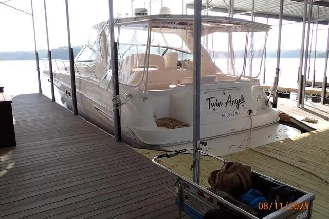 Slide: The Image of 2003 Sea Ray 460 Sundancer docked, named "Twin Angels," with clear canopy and serene lake view. - 23