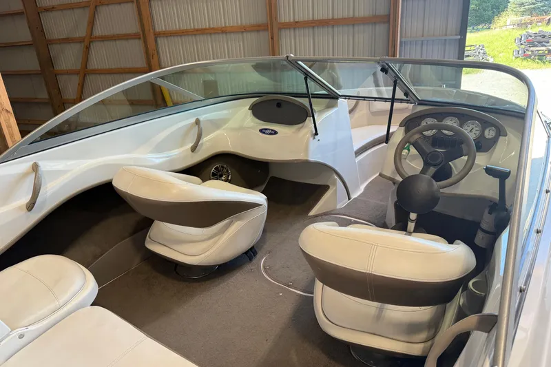 Slide: The Image of 2008 Four Winns H183FS boat interior with white seats and steering wheel in a wooden shed. - 3
