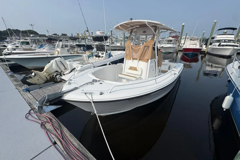 Slide: The Image of 2023 Edgewater 208CC boat docked at marina, surrounded by other vessels. - 0