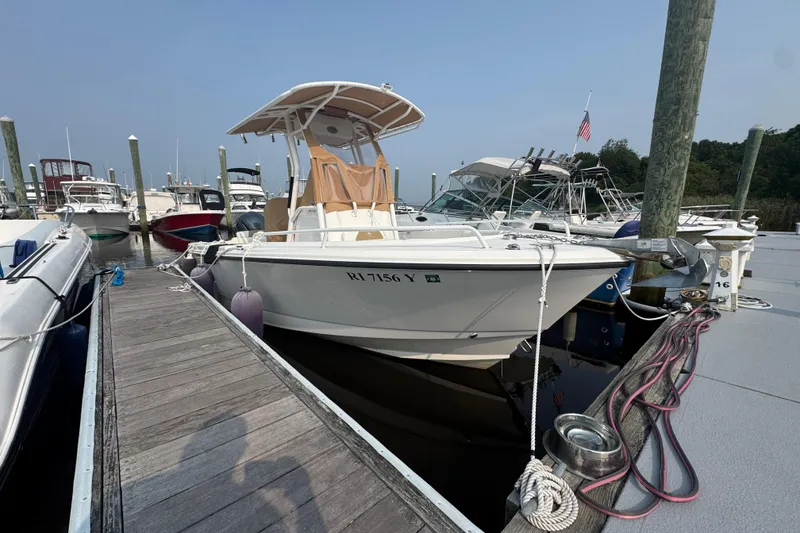 Slide: The Image of 2023 Edgewater 208CC boat docked at a marina with other vessels. - 1