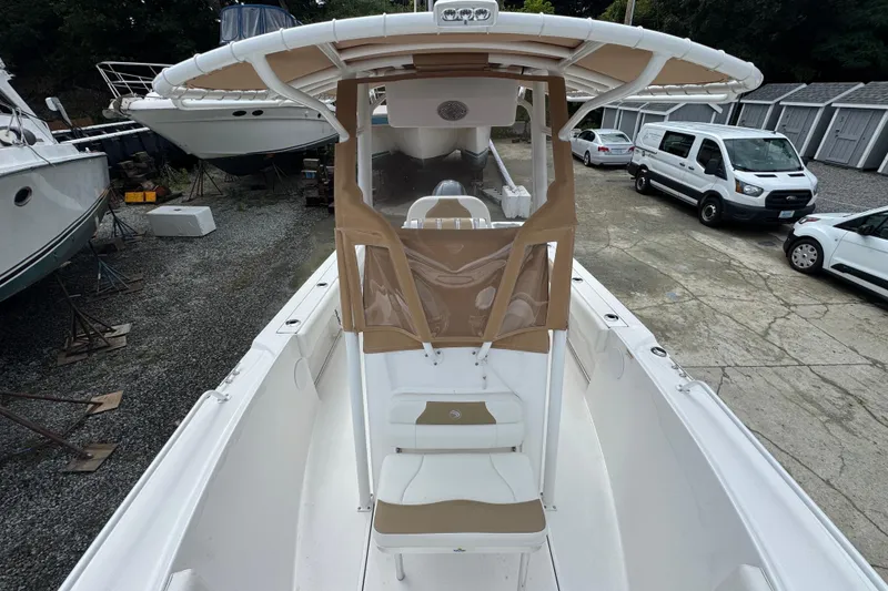 Slide: The Image of 2023 Edgewater 208CC boat with tan canopy, parked near other boats and vehicles. - 14