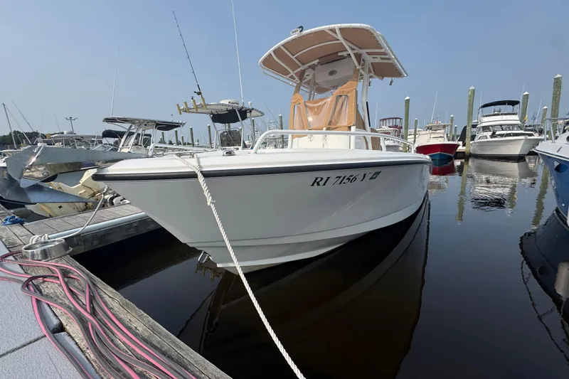 Slide: The Image of 2023 Edgewater 208CC boat docked in a marina, surrounded by other vessels. - 2