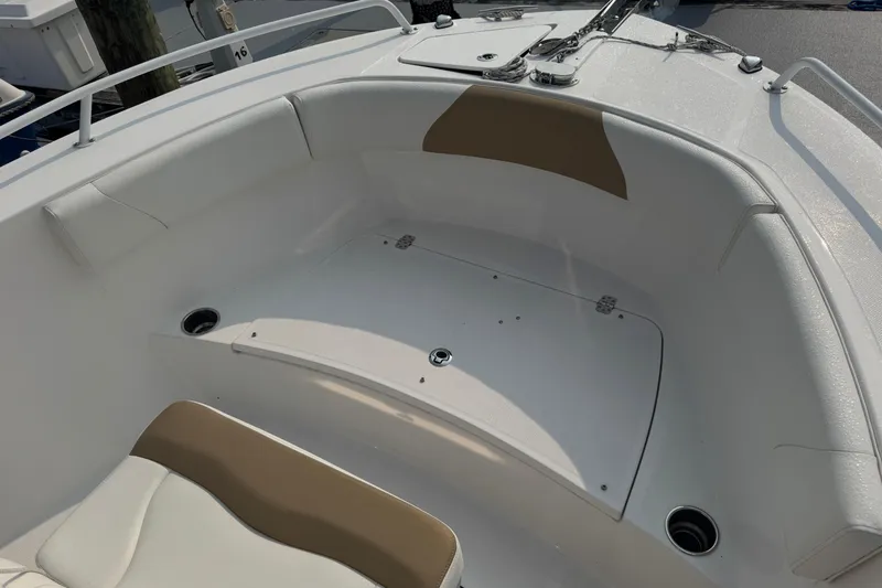 Slide: The Image of 2023 Edgewater 208CC boat interior with cushioned seating and storage compartment. - 27