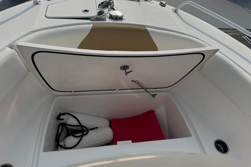 Slide: The Image of Open storage compartment on 2023 Edgewater 208CC boat with fenders and red cushion. - 28