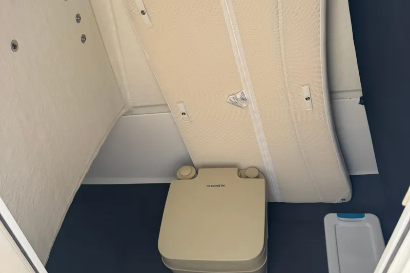 Slide: The Image of 2023 Edgewater 208CC boat interior with portable toilet and storage area. - 32