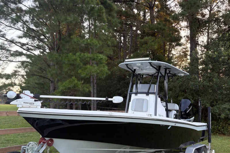 Slide: The Image of 2022 BlackJack 256 Bay boat on trailer, surrounded by trees. - 10