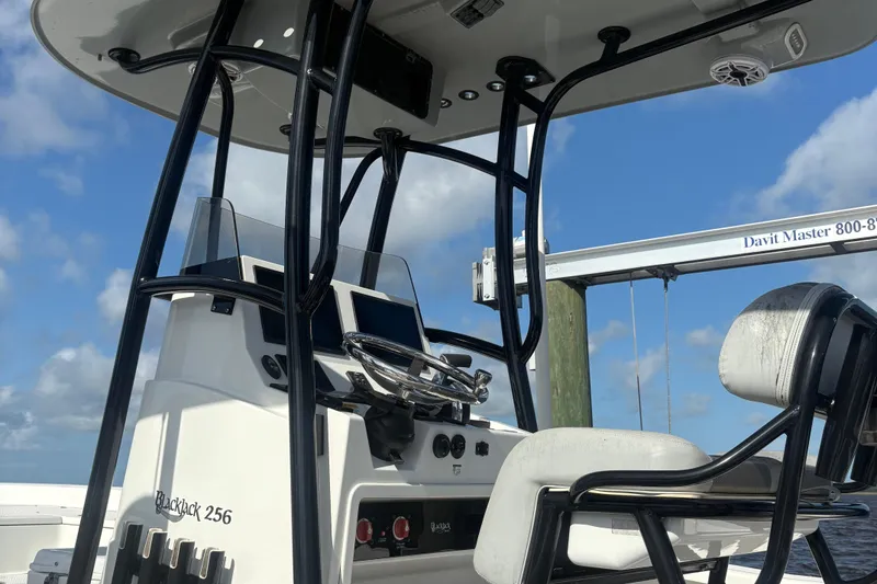 Slide: The Image of 2022 BlackJack 256 Bay boat console with steering wheel and seating under blue sky. - 3