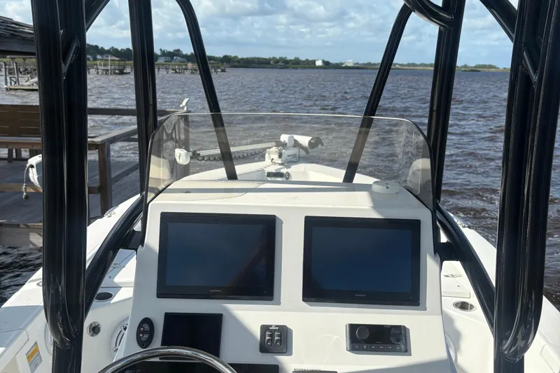 Slide: The Image of 2022 BlackJack 256 Bay boat dashboard with dual screens, steering wheel, and water view. - 5