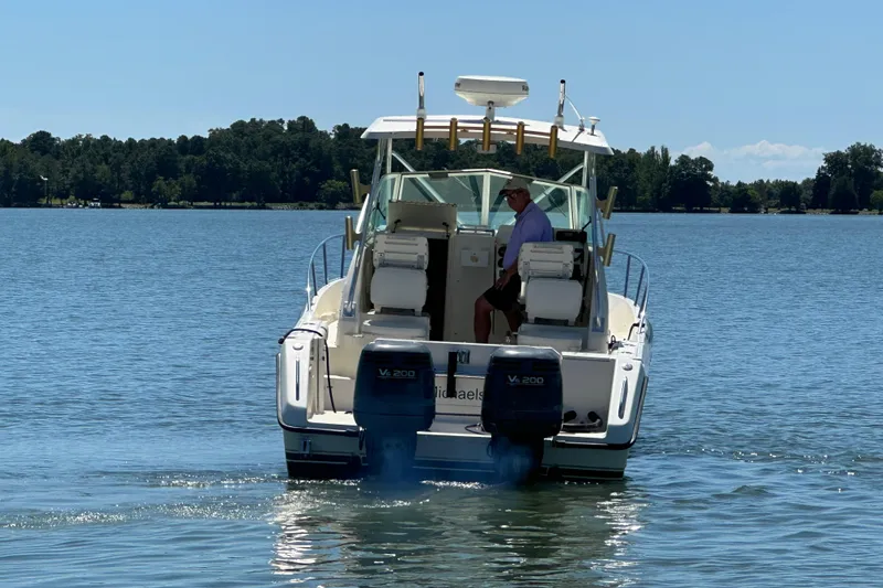 Slide: The Image of 2000 Pursuit 2870 Walkaround boat cruising on a serene lake. - 3