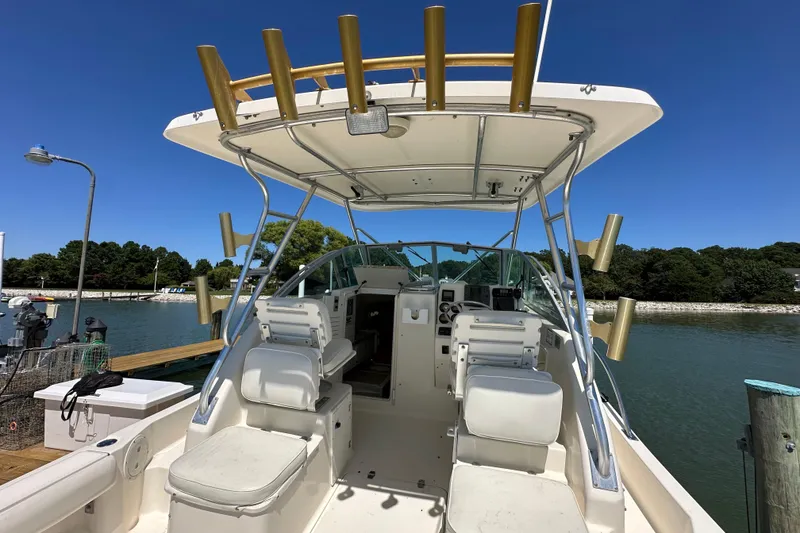 Slide: The Image of 2000 Pursuit 2870 Walkaround boat docked, featuring spacious seating and fishing rod holders. - 5