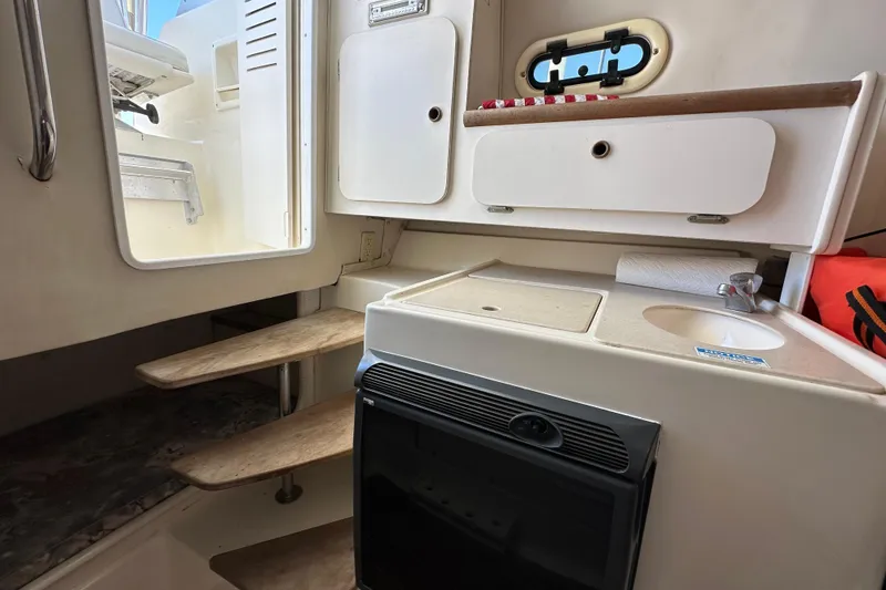 Slide: The Image of 2000 Pursuit 2870 Walkaround cabin interior with kitchenette and stairs. - 8