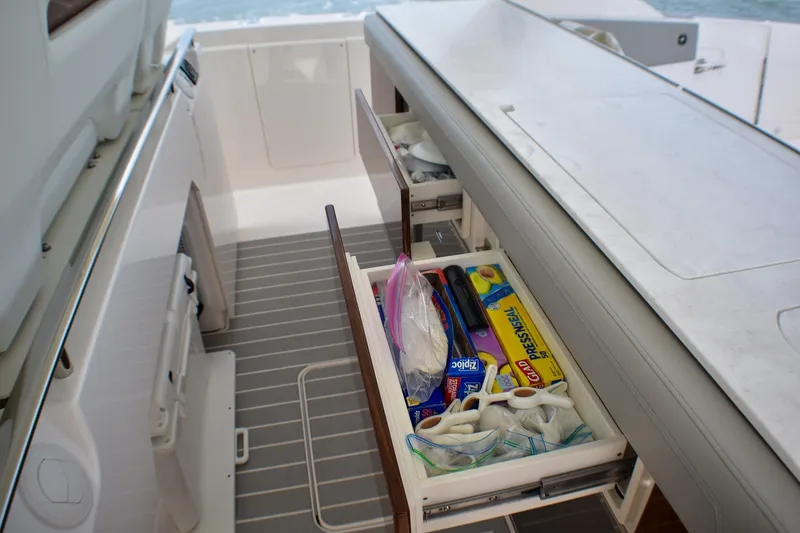 Slide: The Image of 2025 Tiara Yachts 43 LS with open storage drawer containing kitchen supplies. - 36