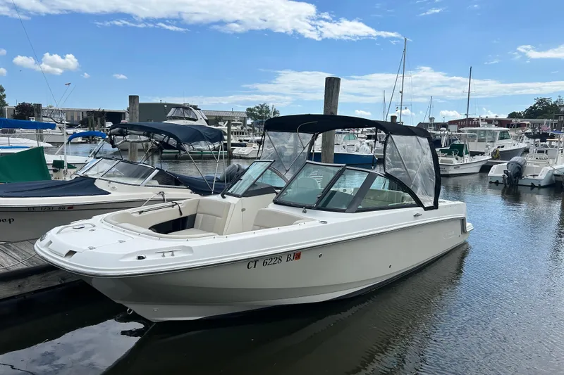 Slide: The Image of 2017 Boston Whaler 230 Vantage boat docked in a marina under a clear blue sky. - 2