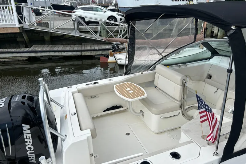 Slide: The Image of 2017 Boston Whaler 230 Vantage boat with seating, table, and American flag at dock. - 4
