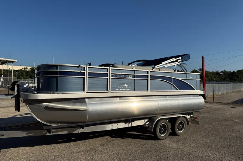 Slide: The Image of 2021 Bennington 20SFi pontoon boat on trailer, parked outdoors under clear sky. - 21