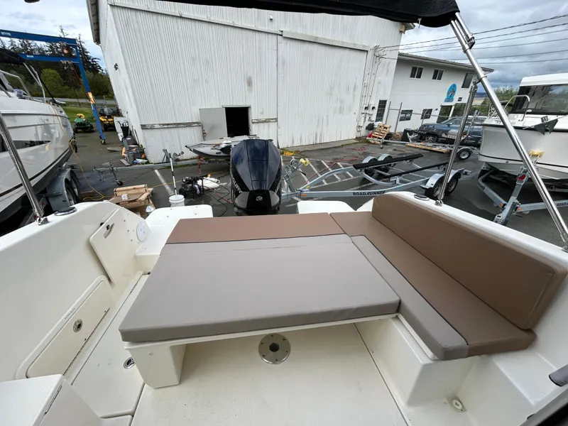 Slide: The Image of 2023 Bayliner Trophy T23 Explorer boat interior with cushioned seating in a marina setting. - 12