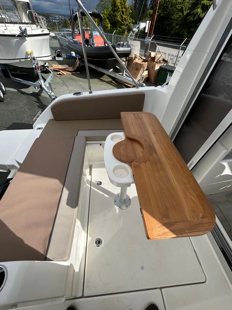 Slide: The Image of 2023 Bayliner Trophy T23 Explorer boat interior with wooden table and seating area. - 13