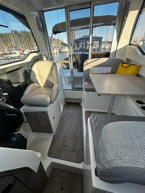 Slide: The Image of 2023 Bayliner Trophy T23 Explorer interior with seating and table, docked at marina. - 5