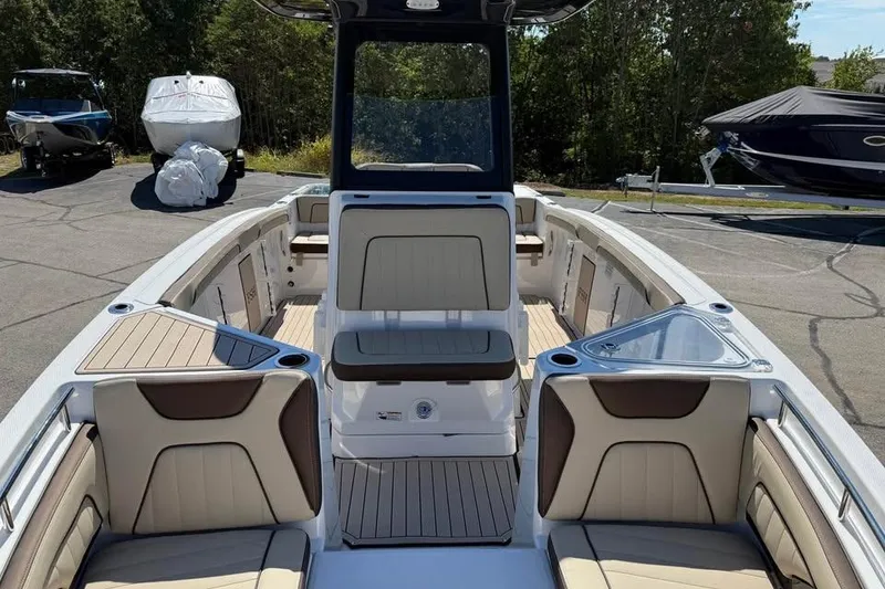 Slide: The Image of 2026 Yamaha Boats 255 FSH Sport H interior with seating and console, parked outdoors. - 15