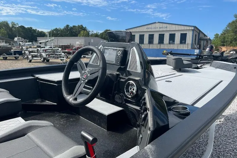 Slide: The Image of 2026 Xpress H20 Bass boat interior with steering wheel and control panel, parked outdoors. - 7