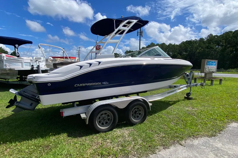 The Image of 2020 Chaparral 19 SSi boat on trailer, parked on grass under a blue sky. - 1