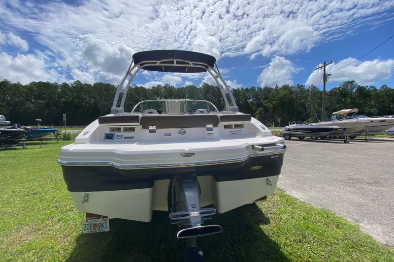Slide: The Image of 2020 Chaparral 19 SSi boat, rear view, parked on grass under a cloudy sky. - 5