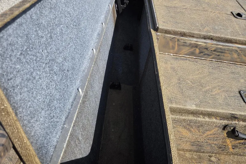 Slide: The Image of 2021 G3 Sportsman 1710 boat storage compartment with carpeted interior and camo-patterned lid. - 9