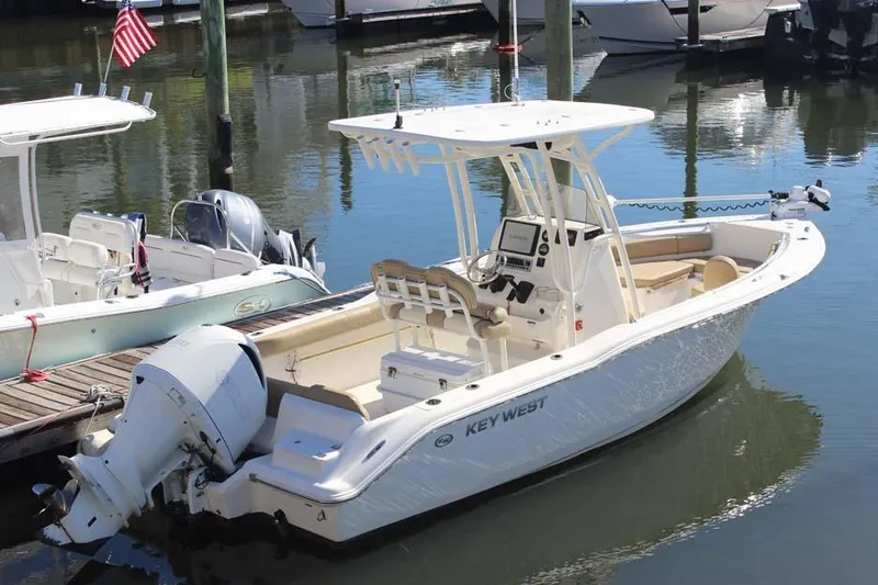 Slide: The Image of 2017 Key West 239 FS boat docked in a marina, featuring a sleek design and outboard motor. - 2