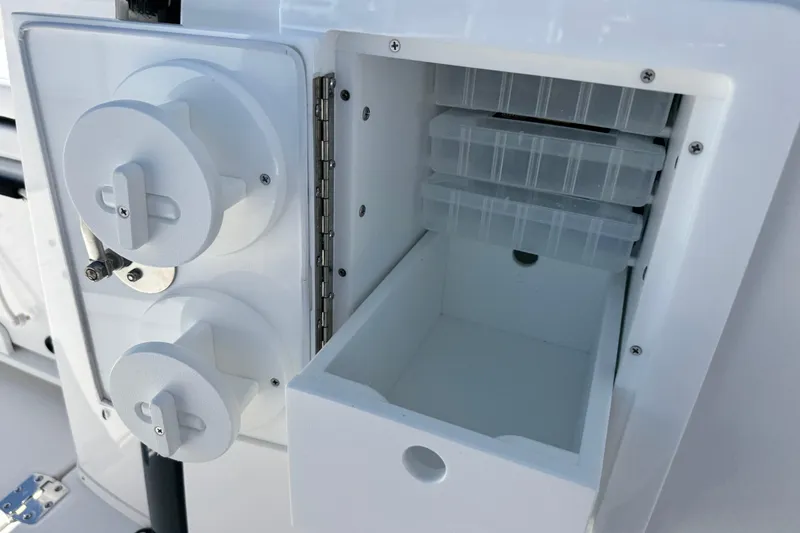 Slide: The Image of 2026 Caymas 34 CT boat storage compartment with tackle boxes and control knobs. - 22