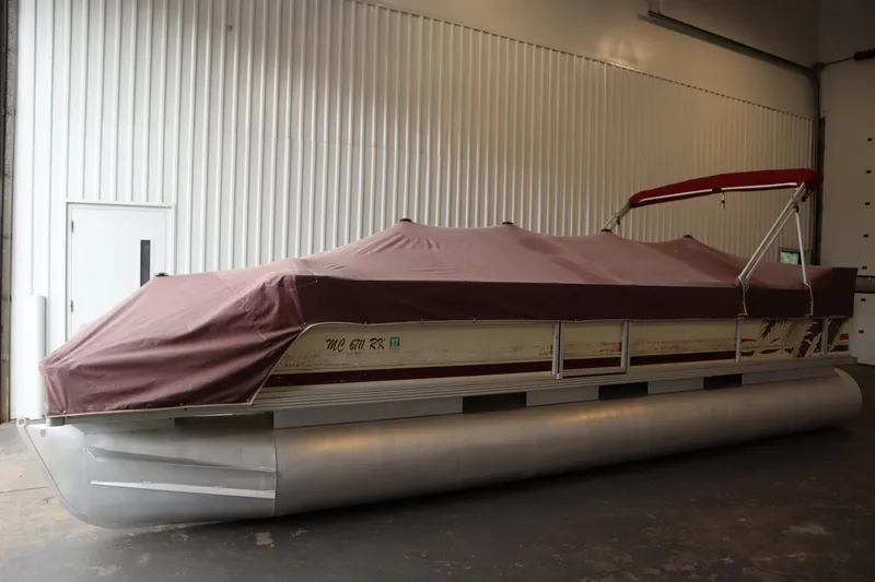 Slide: The Image of 1997 Crest 25 Caribbean pontoon boat with maroon cover in indoor storage. - 33