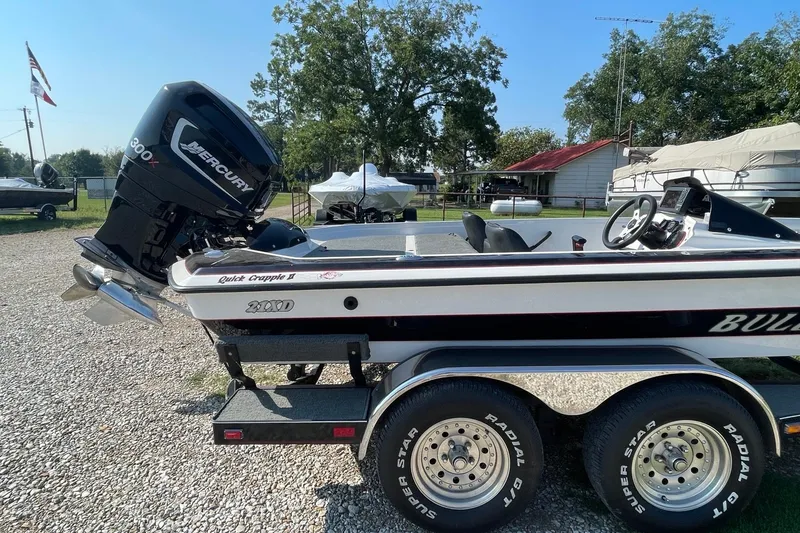 Slide: The Image of 2000 Bullet 21XD boat with Mercury 300X engine on a trailer, parked outdoors. - 6