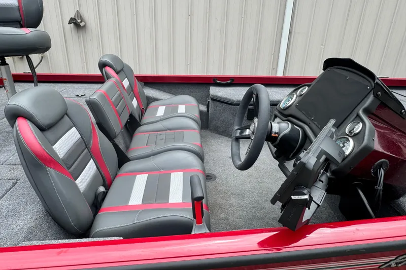 Slide: The Image of 2024 Bass Tracker RT178 boat interior with gray and red seating, steering wheel, and dashboard. - 12